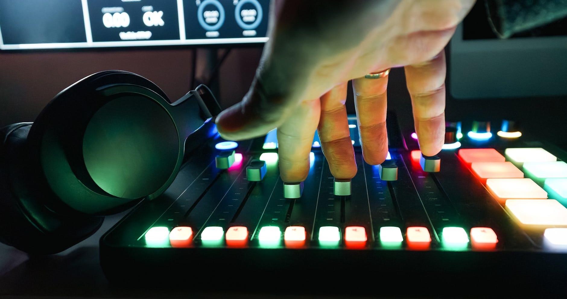 Dłoń regulująca suwaki kolorowego miksera dźwięku w studiu nagrań