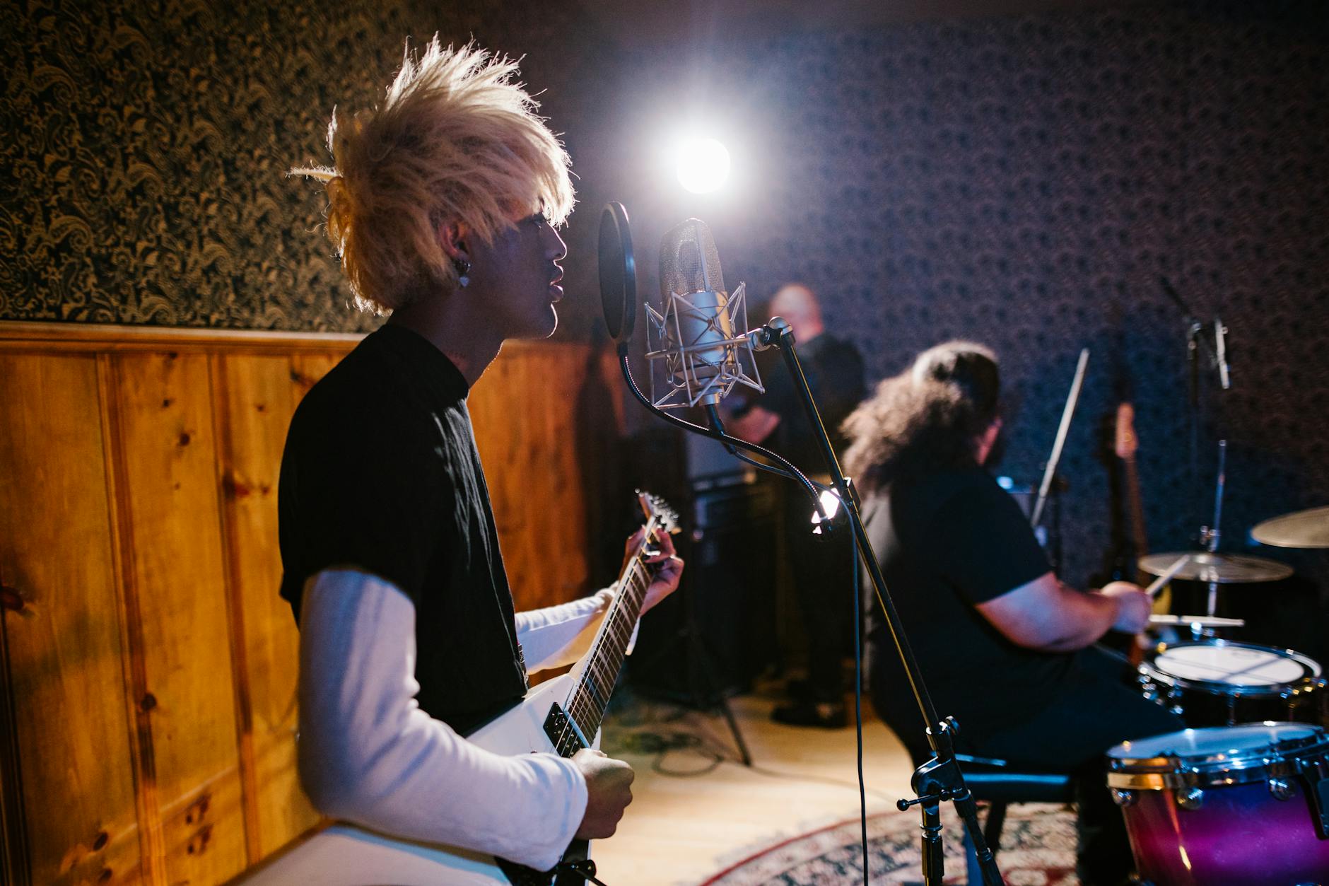 Zespół rockowy ćwiczy na żywo w studiu, gitarzysta i perkusista