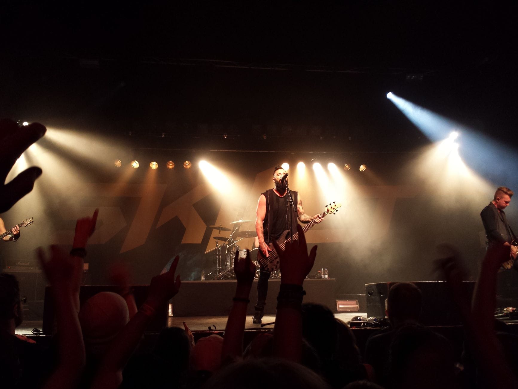 Rockowy zespół na scenie, kolorowe światła i żywiołowa publiczność