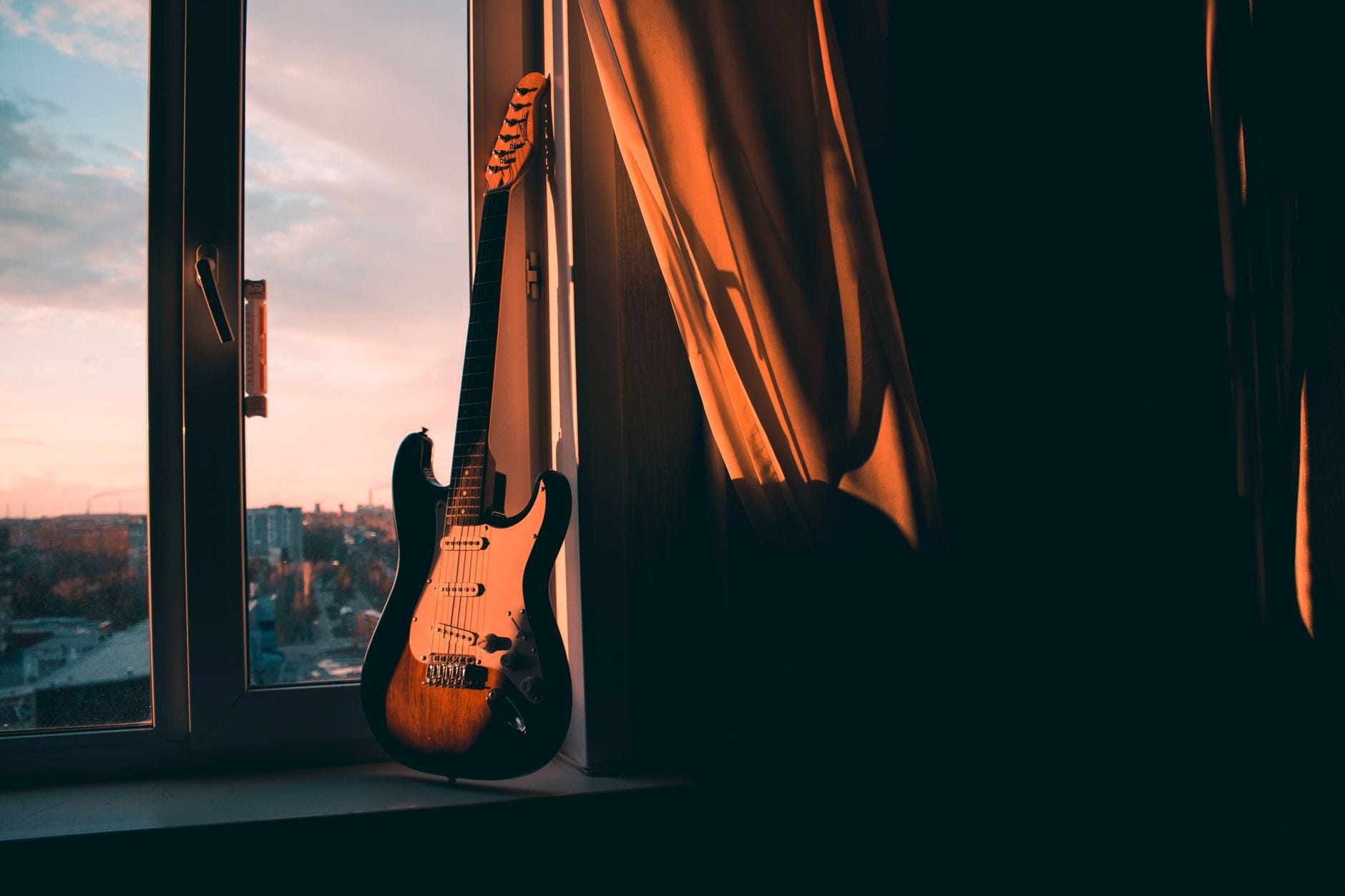 Elektryczna gitara oparta o okno w blasku zachodu słońca