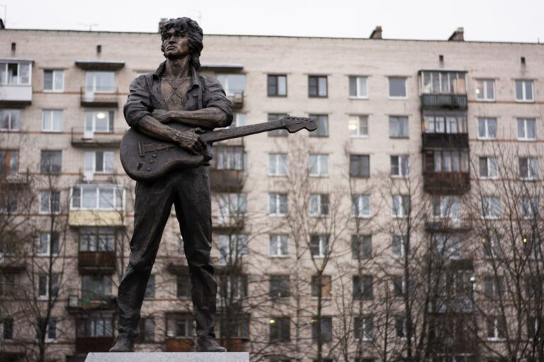 Pomnik muzyka z gitarą na tle miejskiego bud